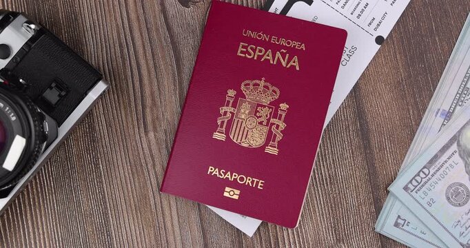 Sleek overhead angle of a red spain passport cover book resting next to commercial flight tickets on a dark wooden table element