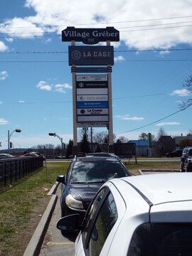 Gatineau, Quebec, Canada &ndash; May 9, 2026: A tall commercial sign for "Village Gr&eacute;ber" lists various businesses and is positioned in front of a parking area on Bd Gr&eacute;ber.
