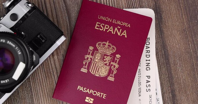 Overhead look of an official red spain passport document next to custom airline flight tickets on a vintage dark wooden table