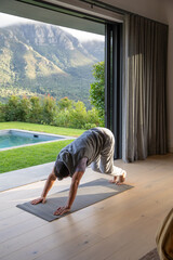 Naklejka premium Yoga mat is lying next to open sliding glass door, sunlight warming wooden floor and pool
