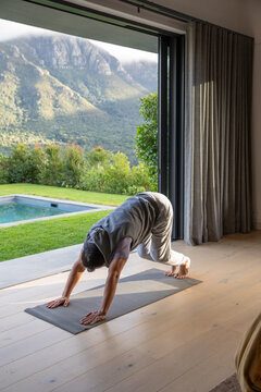 Yoga mat is lying next to open sliding glass door, sunlight warming wooden floor and pool