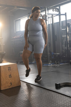 African American female wearing gray workout set stepping up onto plyo box marked 21 or 15 or 9 at g