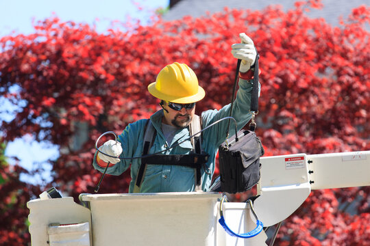 Power engineer in lift bucket working with meter to measure power
