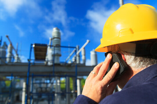 Power engineer talking on a mobile phone at high voltage distribution station