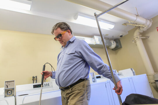 Man with congenital blindness pulling the laundry cart in the laundry room