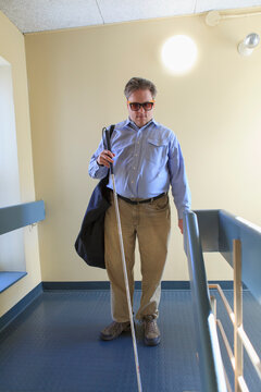 Man with congenital blindness using his cane in an apartment hallway