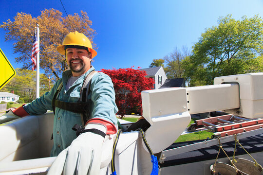 Power engineer in lift bucket with safety equipment for power lines at truck level