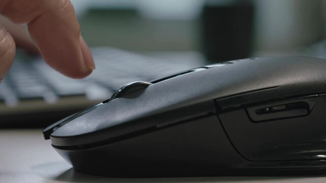 Close-up of finger scrolling on a computer mouse, working on technology