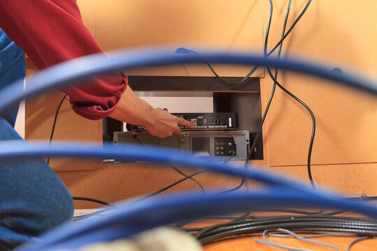 Service man installing new cable box into home TV