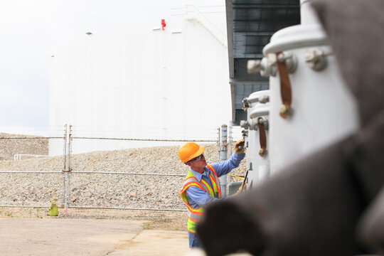 Electrical engineer examining spare power transformers with fuel tank storage in background