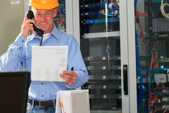 Electrical engineer working with switches and servers in broadband communication hub looking at