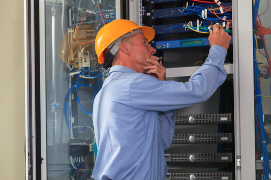 Electrical engineer working with switches and servers in broadband communication hub of electric