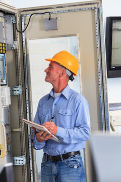 Electrical engineer inspecting power plant controls in central operations room of power plant