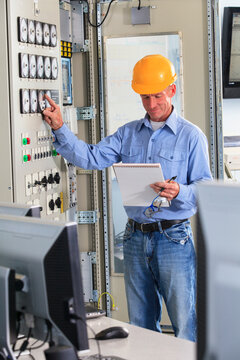 Electrical engineer inspecting power plant controls in central operations room of power plant