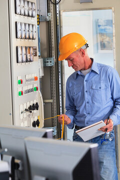 Electrical engineer inspecting power plant controls in central operations room of power plant