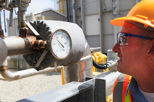 Engineer examining transducer gauge at electric power plant