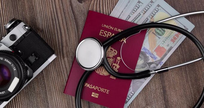 Overhead flat lay view of a medical stethoscope being placed on an international travel passport document over a clean surface