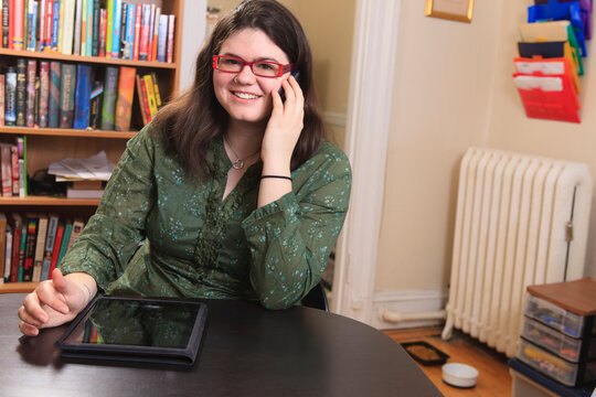Woman with Asperger syndrome working with her smart phone and tablet from home office