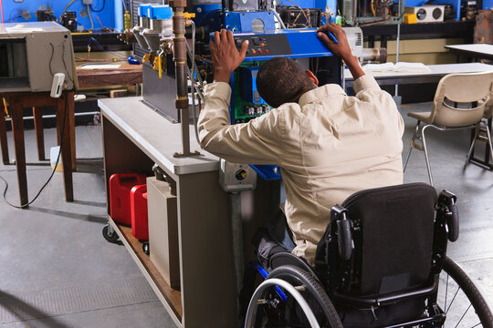 Student in wheelchair studying furnace electronic control system in HVAC classroom