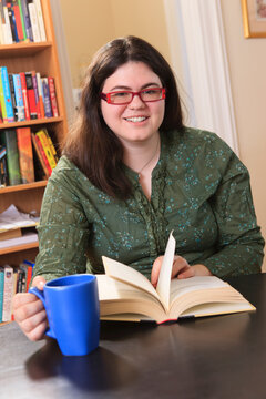 Woman with Asperger syndrome relaxing with a mug of tea and a book