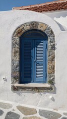 Fototapeta premium Iconic Mediterranean architectural detail featuring a rustic blue wooden window shutter encased in natural stone masonry on a brilliant white stucco wall, sun-drenched facade, travel lifestyle vibe.