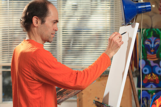 Man with Asperger's drawing his outline for his painting in his art studio