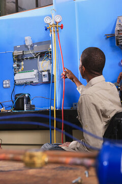 Student in wheelchair studying air conditioner test gauges in HVAC classroom