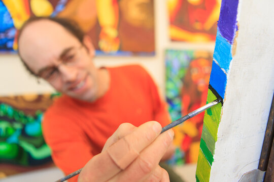 Man with Asperger's painting in his art studio