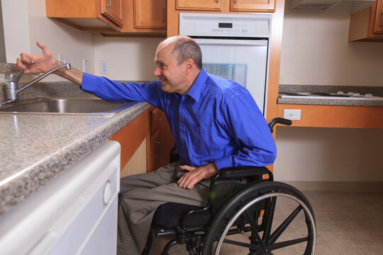 Man with Friedreich's Ataxia and deformed hands using his faucet in the kitchen
