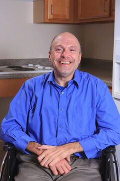 Man with Friedreich's Ataxia and deformed hands sitting in his wheelchair and smiling