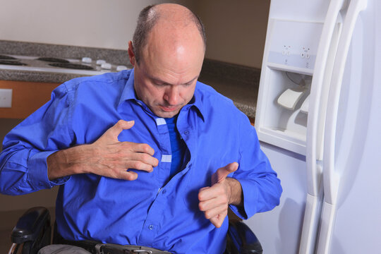 Man in a wheelchair with disabled hands fastens shirt up the front with touch fasteners