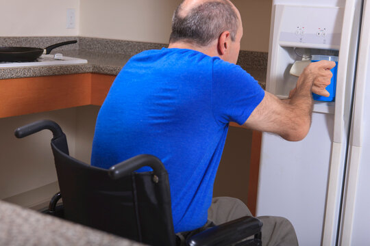 Man with Friedreich's Ataxia and deformed hands using the water dispenser in his refrigerator