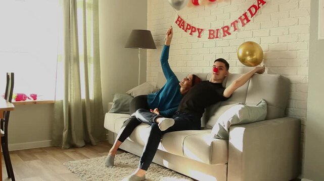 Son fixes golden balloon while sitting on sofa with mom