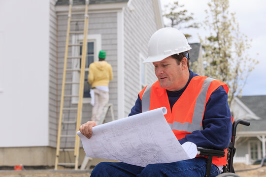 Construction engineer with spinal cord injury with house plans at construction site