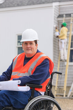 Construction engineer with spinal cord injury with house plans at construction site