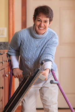 Woman with Cerebral Palsy using crutches and opening her oven in her kitchen