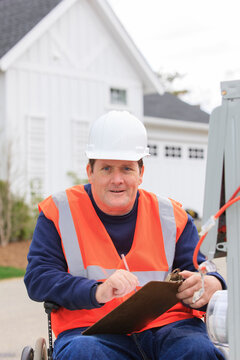 Construction engineer with spinal cord injury taking notes at temporary utility box