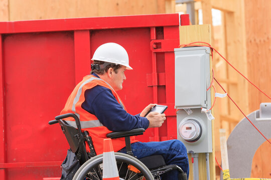 Construction engineer with spinal cord injury using tablet to take notes at temporary utility box