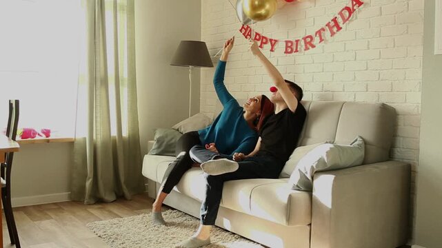 Mother and son playing with balloons while sitting on the sofa