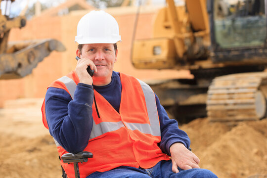 Construction engineer with spinal cord injury on radio to equipment operator