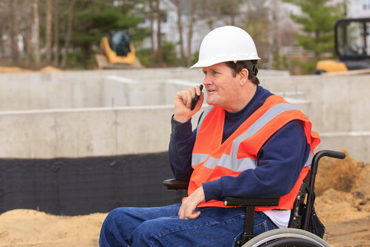 Construction engineer with spinal cord injury on radio at foundation site