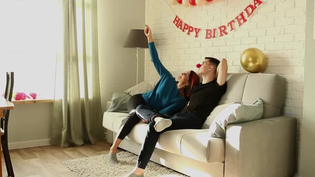 Mother playing with balloon while sitting on sofa with son