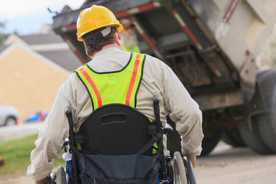 Construction supervisor with Spinal Cord Injury watching dump truck