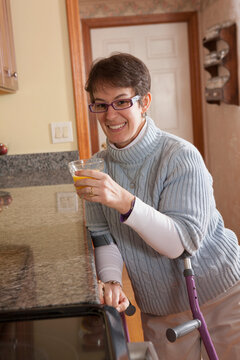 Woman with Cerebral Palsy using crutches and having juice in her home kitchen