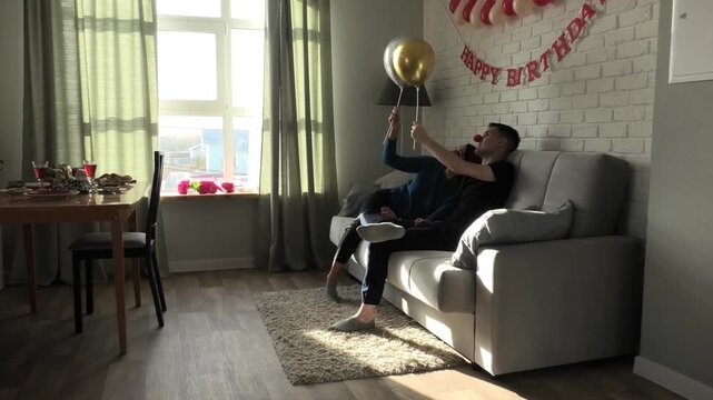 Mother and son playing with balloons while sitting on the sofa