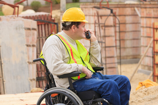 Construction supervisor with Spinal Cord Injury on walkie talkie inspecting concrete foundation