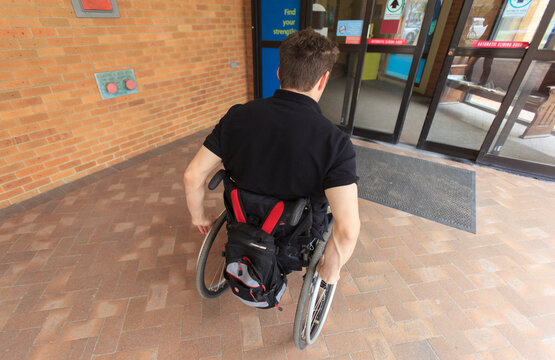 Man with spinal cord injury entering electronic door