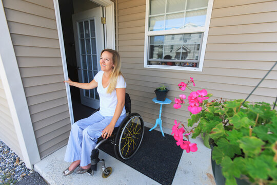 Woman with spinal cord injury in wheelchair coming out of her house