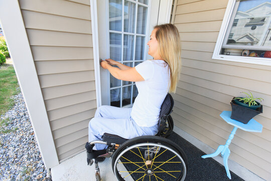 Woman in wheelchair locking the front door of her house