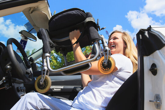 Woman with spinal cord injury pulling chair from wheelchair into her adaptive vehicle